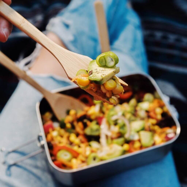 Frau genießt Salat mit samebutgreen nachhaltigem Bambus-Besteckset bei Picknick aus plastikfreier Edelstahl Doppellunchbox.